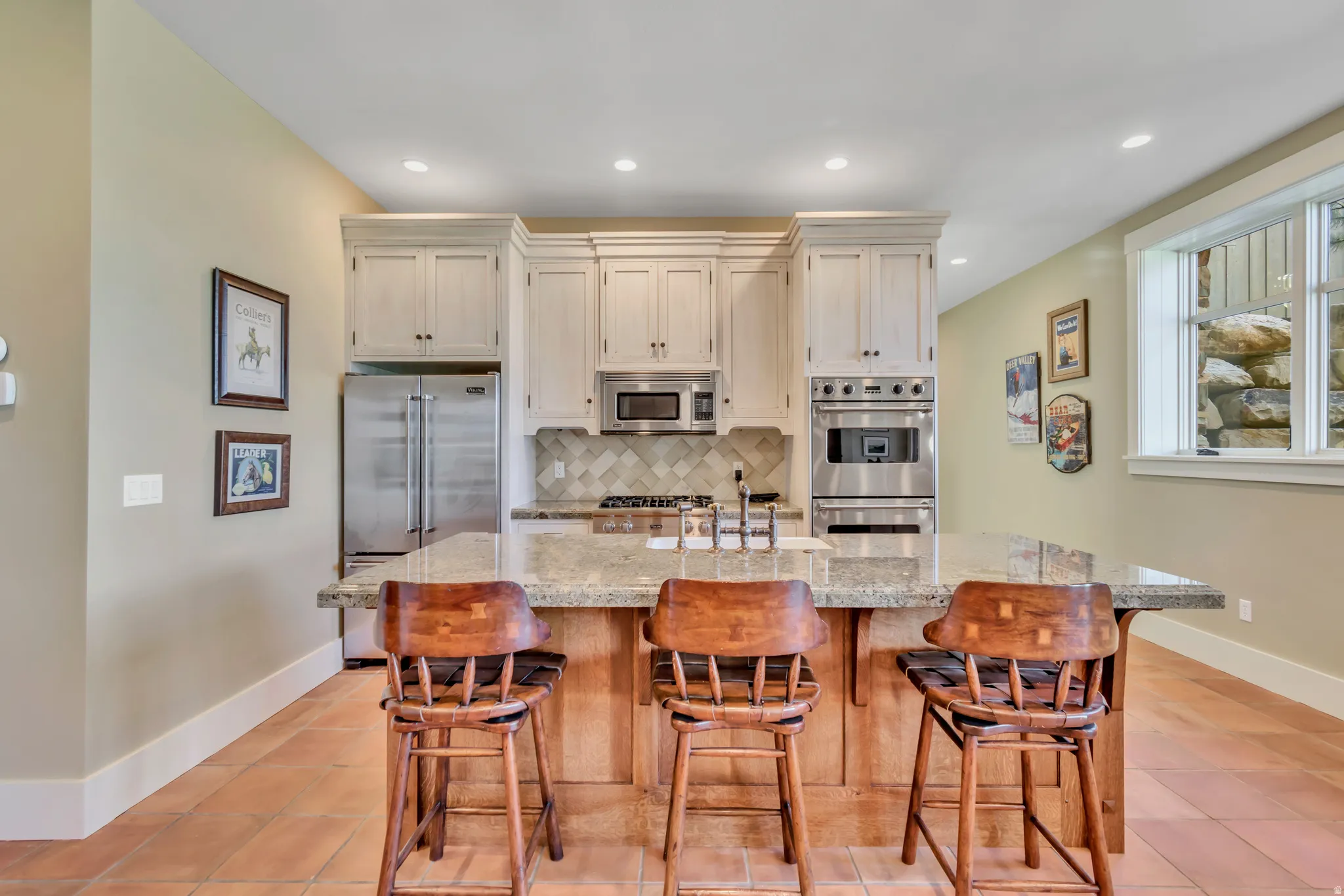 Kitchen with stainless steel appliances, a kitchen island with sink, light stone counters, tasteful backsplash, and recessed lighting