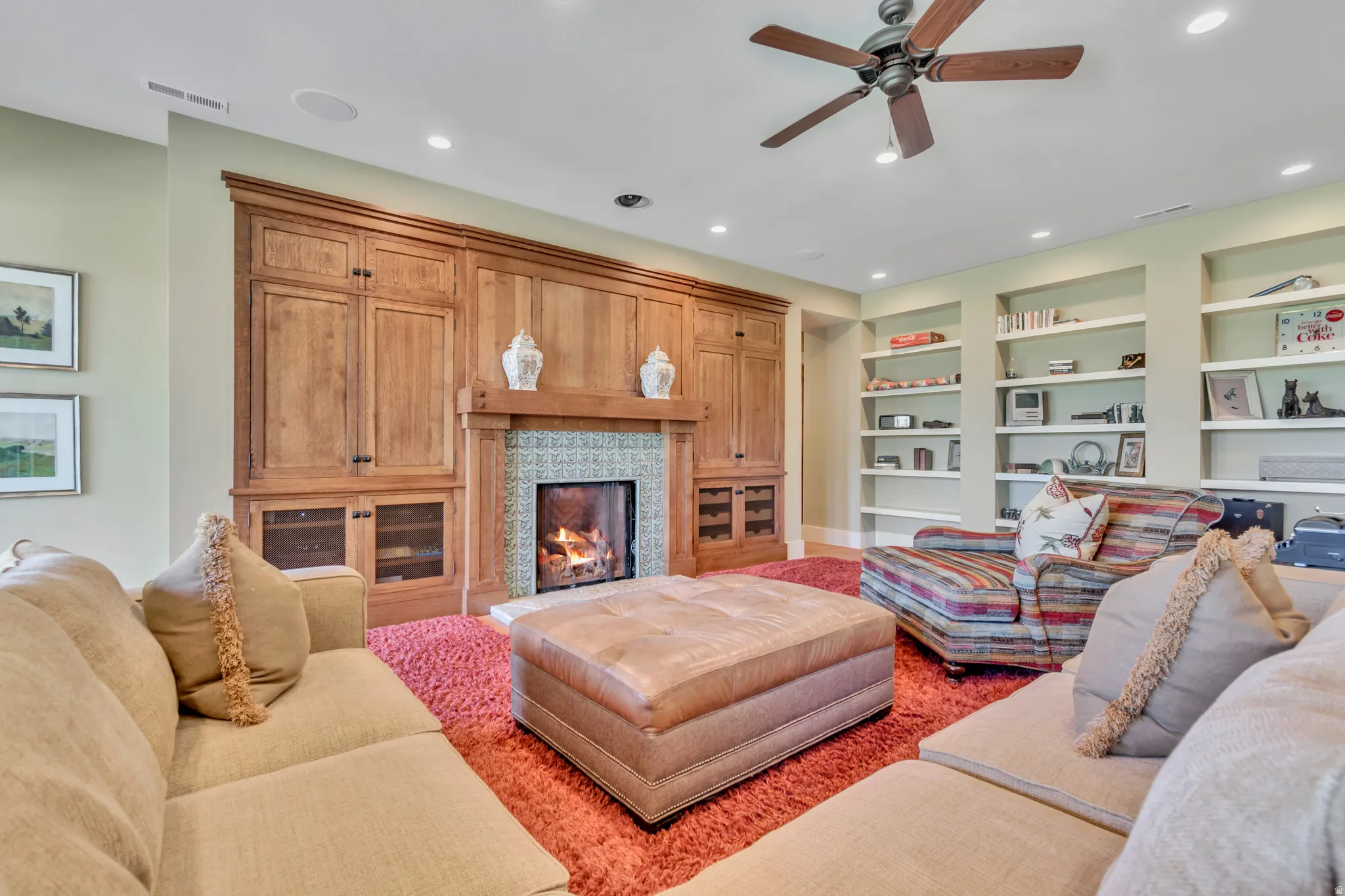 Living room with ceiling fan, a lit fireplace, built in features, and recessed lighting