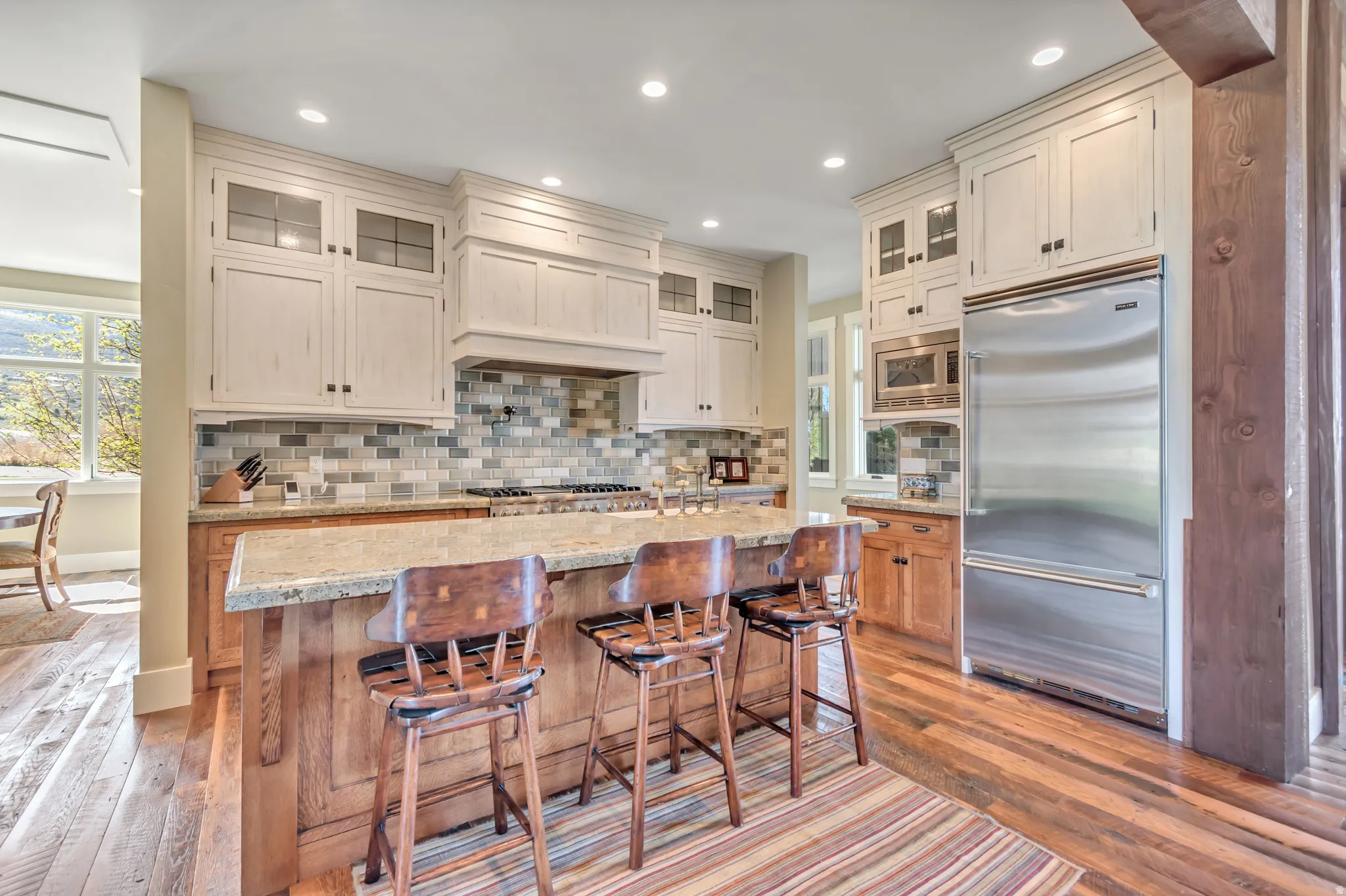 Kitchen with glass insert cabinets, built in appliances, light stone countertops, light wood-type flooring, and recessed lighting