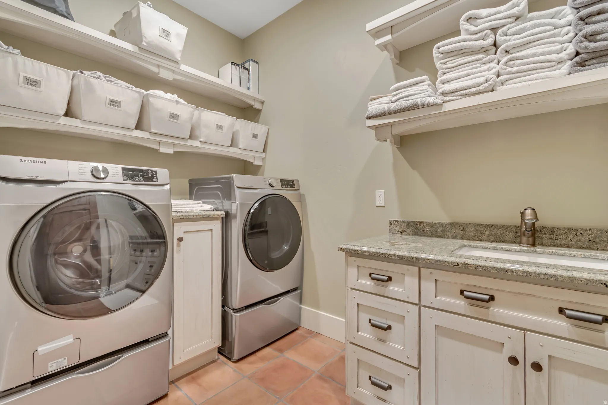 Laundry area featuring separate washer and dryer, cabinet space, and light tile patterned floors