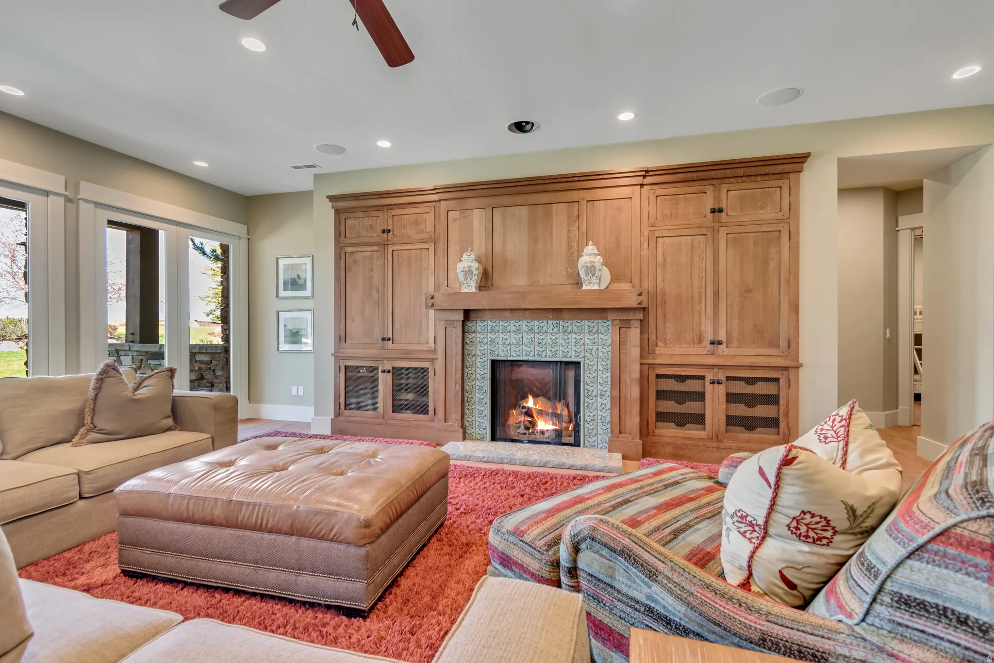 Living area with recessed lighting, ceiling fan, and a warm lit fireplace