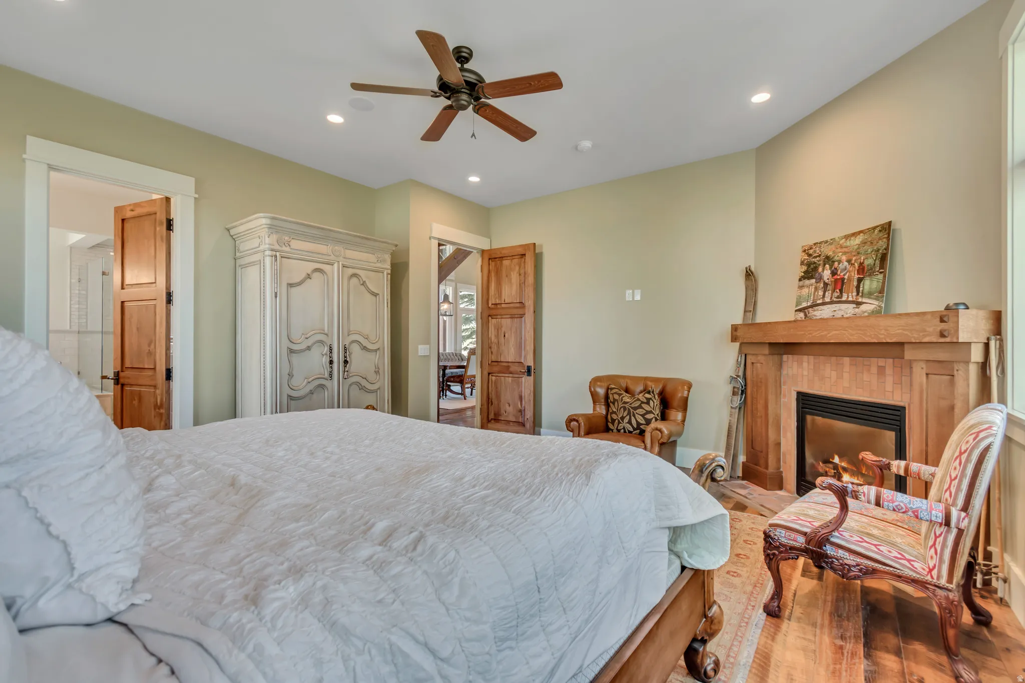 Bedroom featuring recessed lighting, ceiling fan, a tiled fireplace, and wood-type flooring