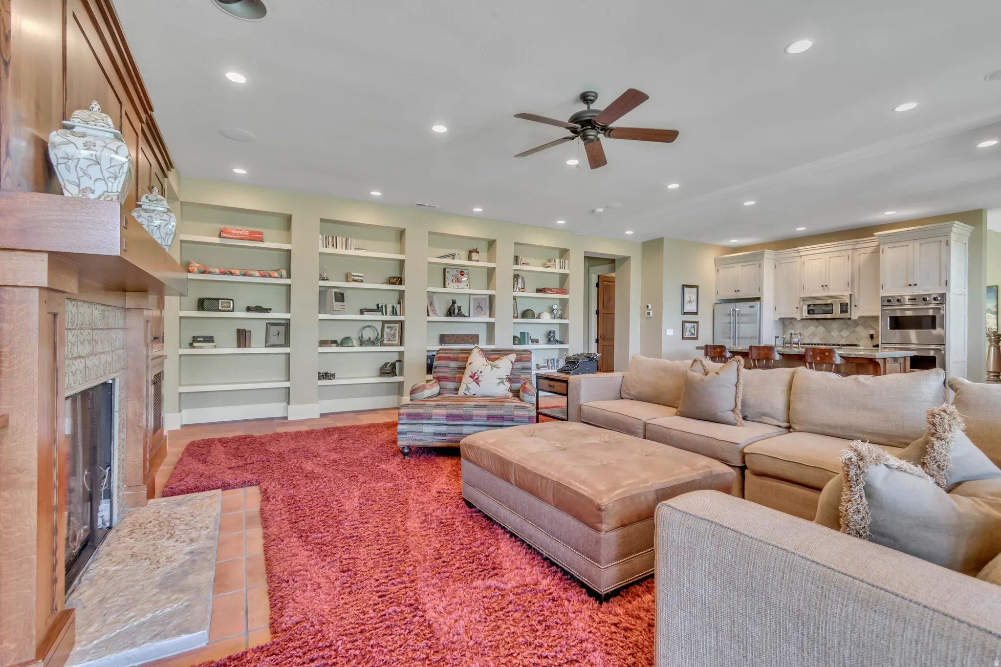 Living room with a ceiling fan, recessed lighting, a glass covered fireplace, and built in shelves