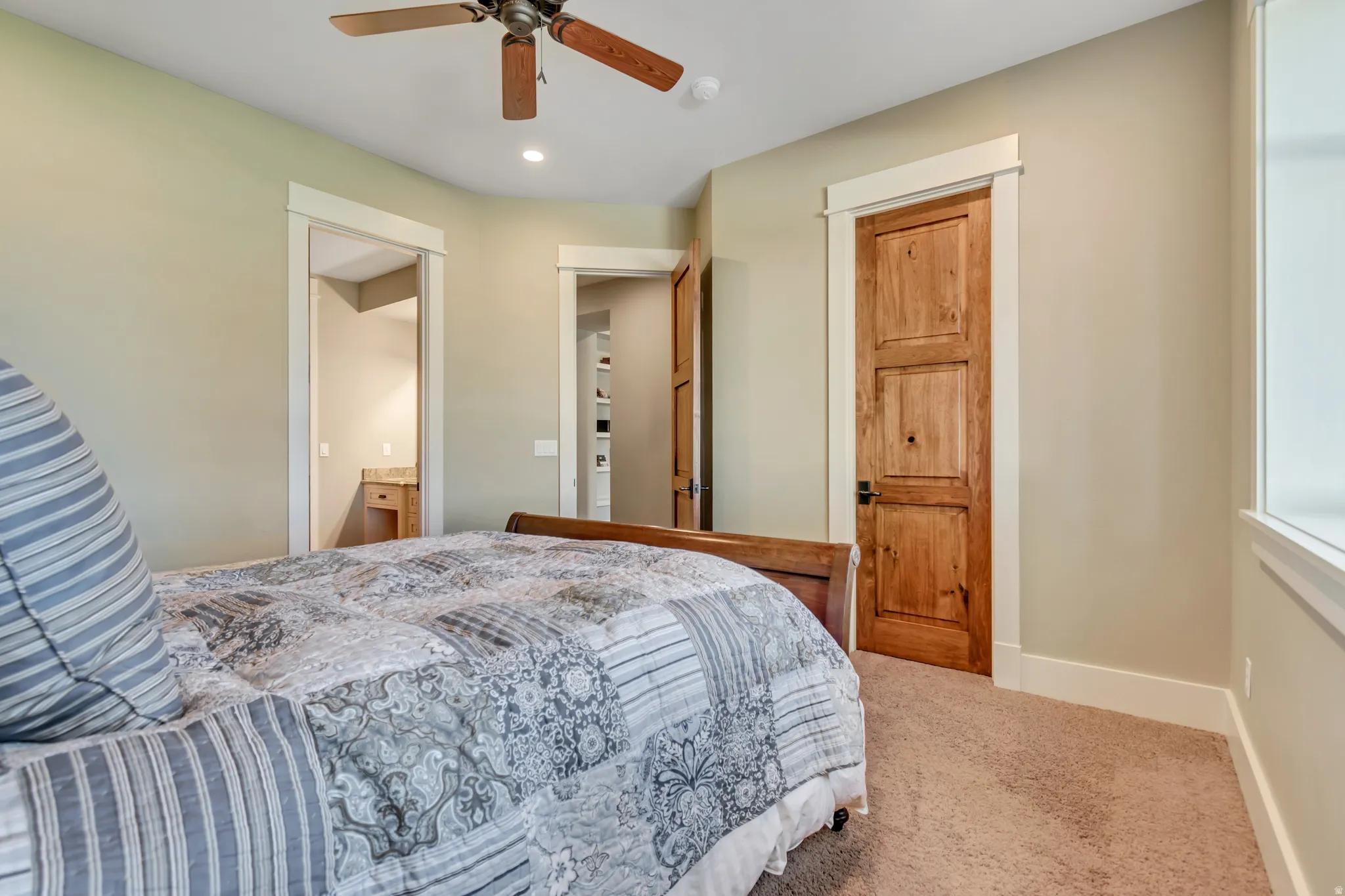 Bedroom with light carpet, ensuite bathroom, a ceiling fan, and recessed lighting