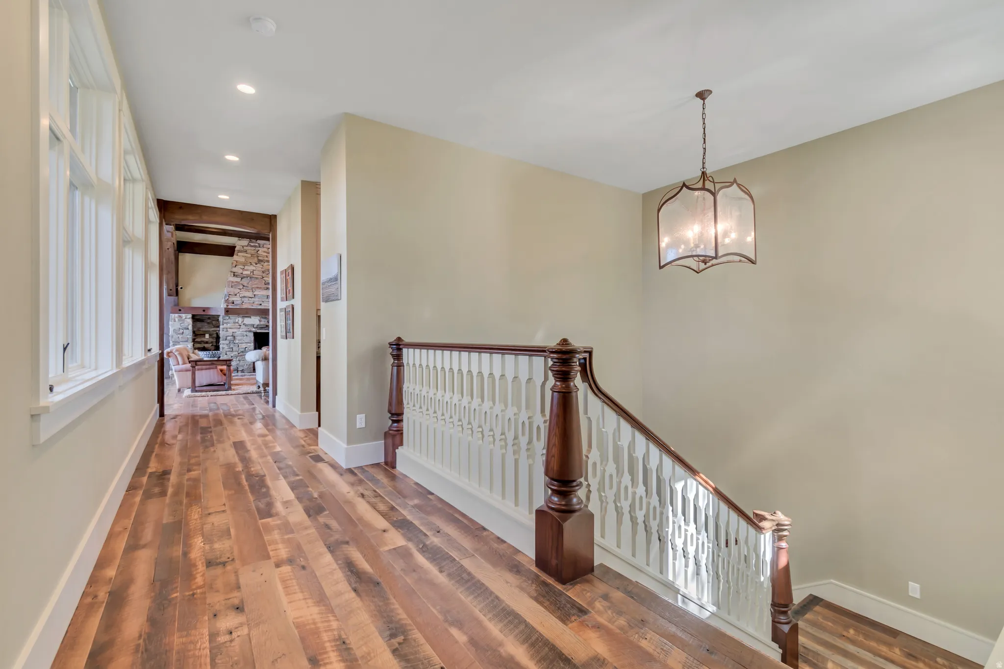 Hall with hardwood / wood-style floors, an upstairs landing, and hanging lights