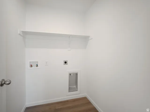 Dedicated laundry area featuring a white wall shelf, utility hookups, and wood-finish flooring