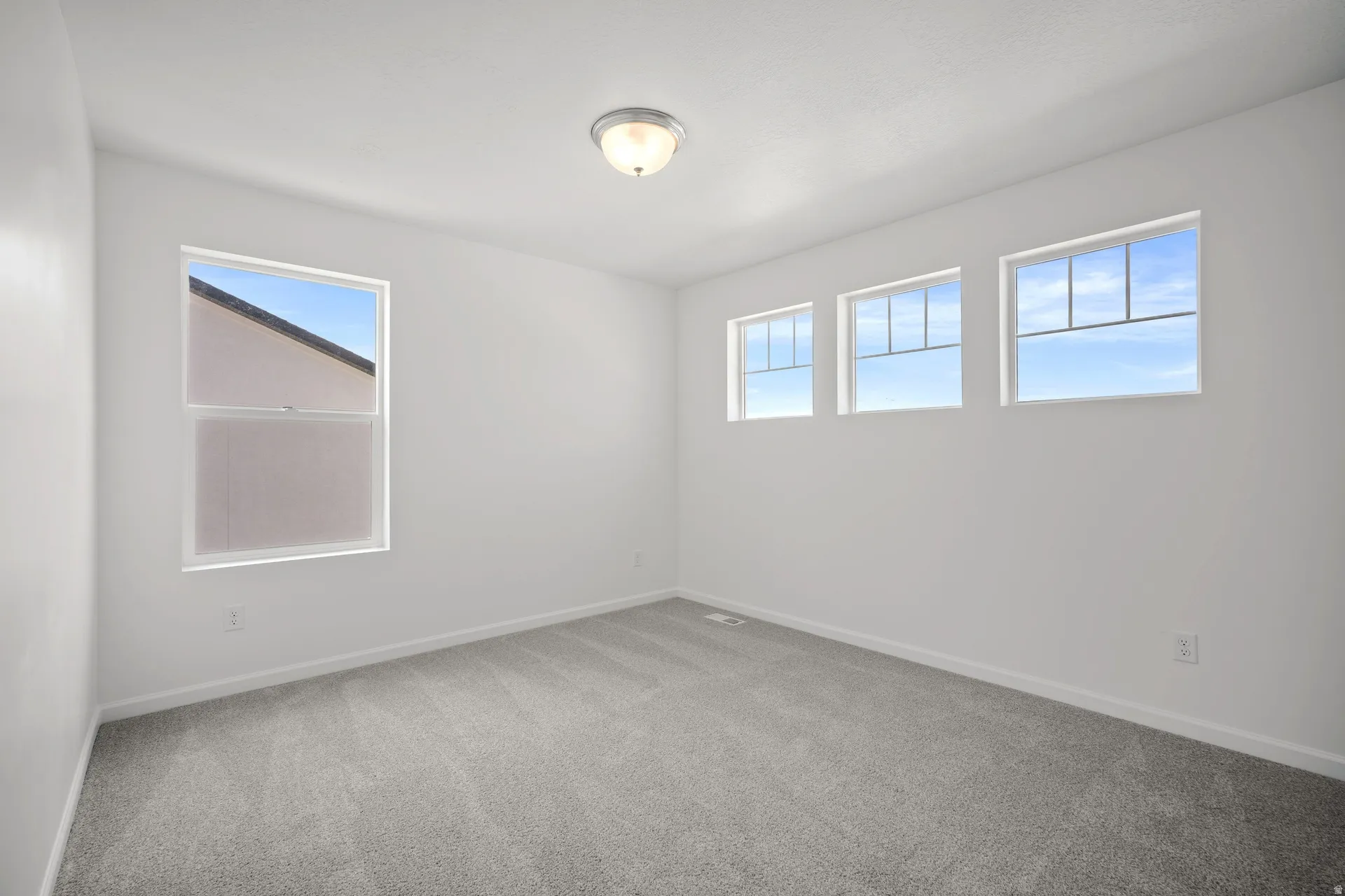 Spacious room featuring light gray carpeting and white walls