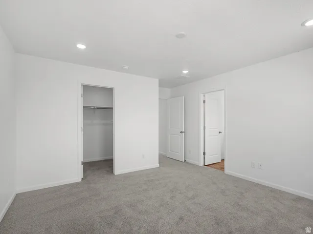 Bright room featuring plush gray carpeting, recessed ceiling lighting, and crisp white walls