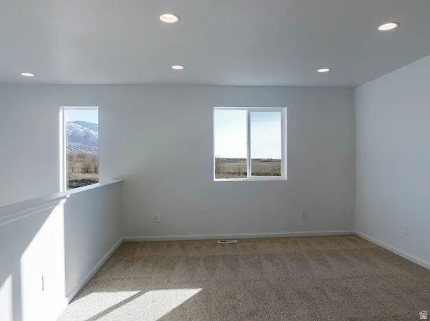 Spare room featuring plenty of natural light, light carpet, and recessed lighting