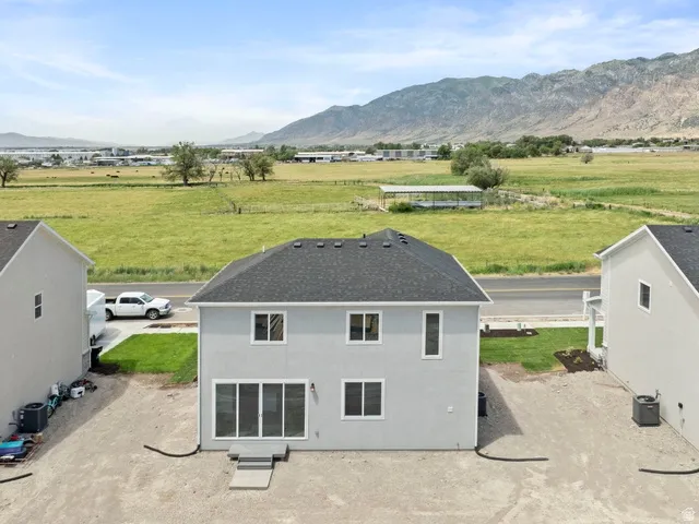 Gray stucco exterior with multiple windows, a dark shingle roof, and a rear patio door