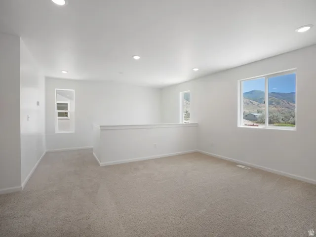 Spacious room with light-colored carpeting and bright white walls