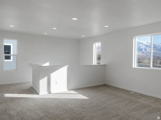 Carpeted spare room with baseboards and recessed lighting