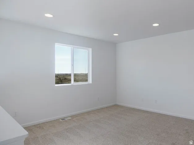 Empty room featuring light colored carpet and recessed lighting