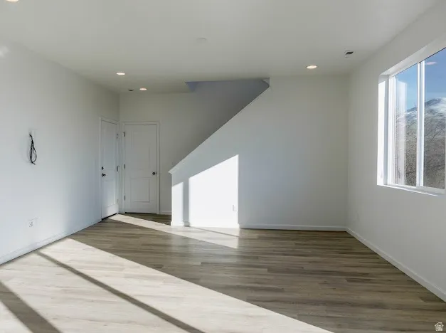 Unfurnished room with wood finished floors and recessed lighting