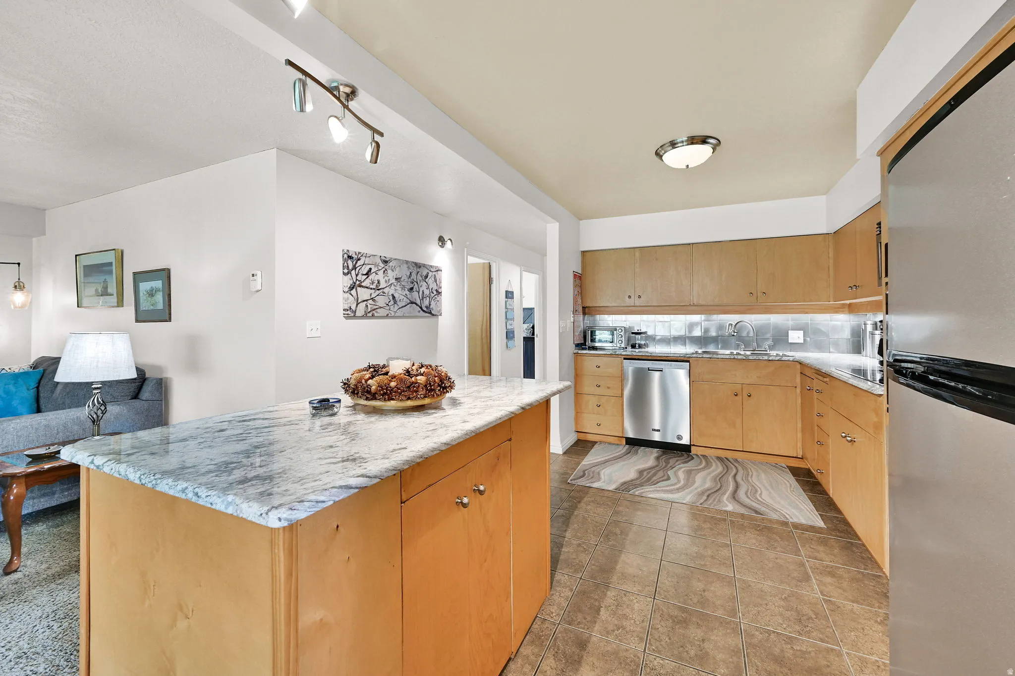 Kitchen with stainless steel appliances, open floor plan, a kitchen island, backsplash, and light tile patterned flooring