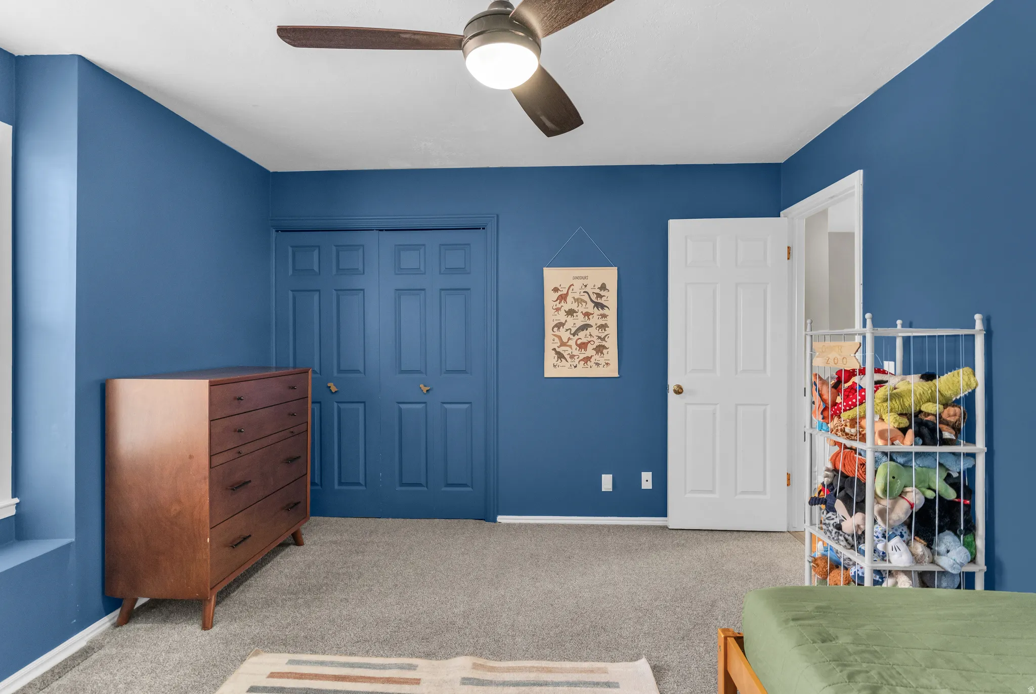 Bedroom with light carpet, a ceiling fan, and a closet