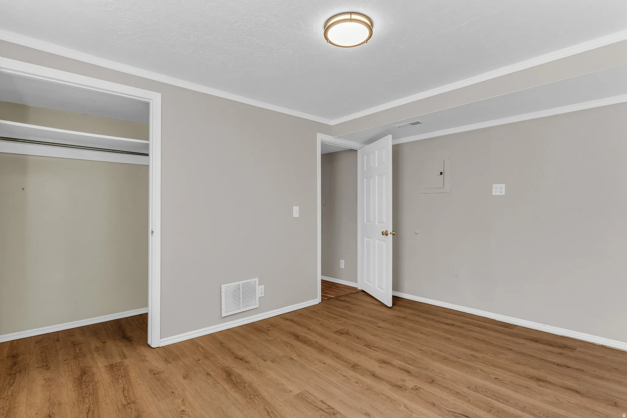 Unfurnished bedroom with light wood-style flooring, ornamental molding, and a closet