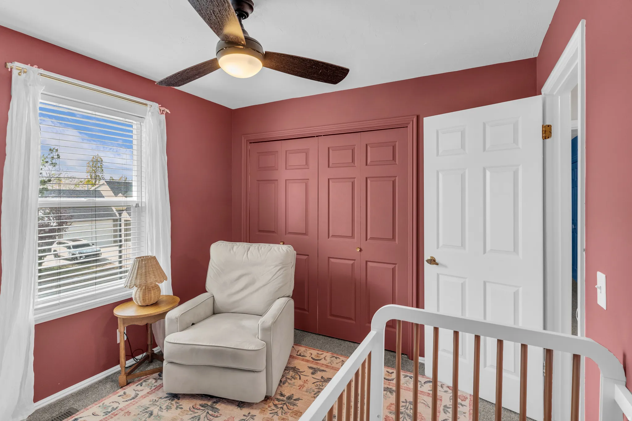 Carpeted bedroom with a crib, a closet, and a ceiling fan