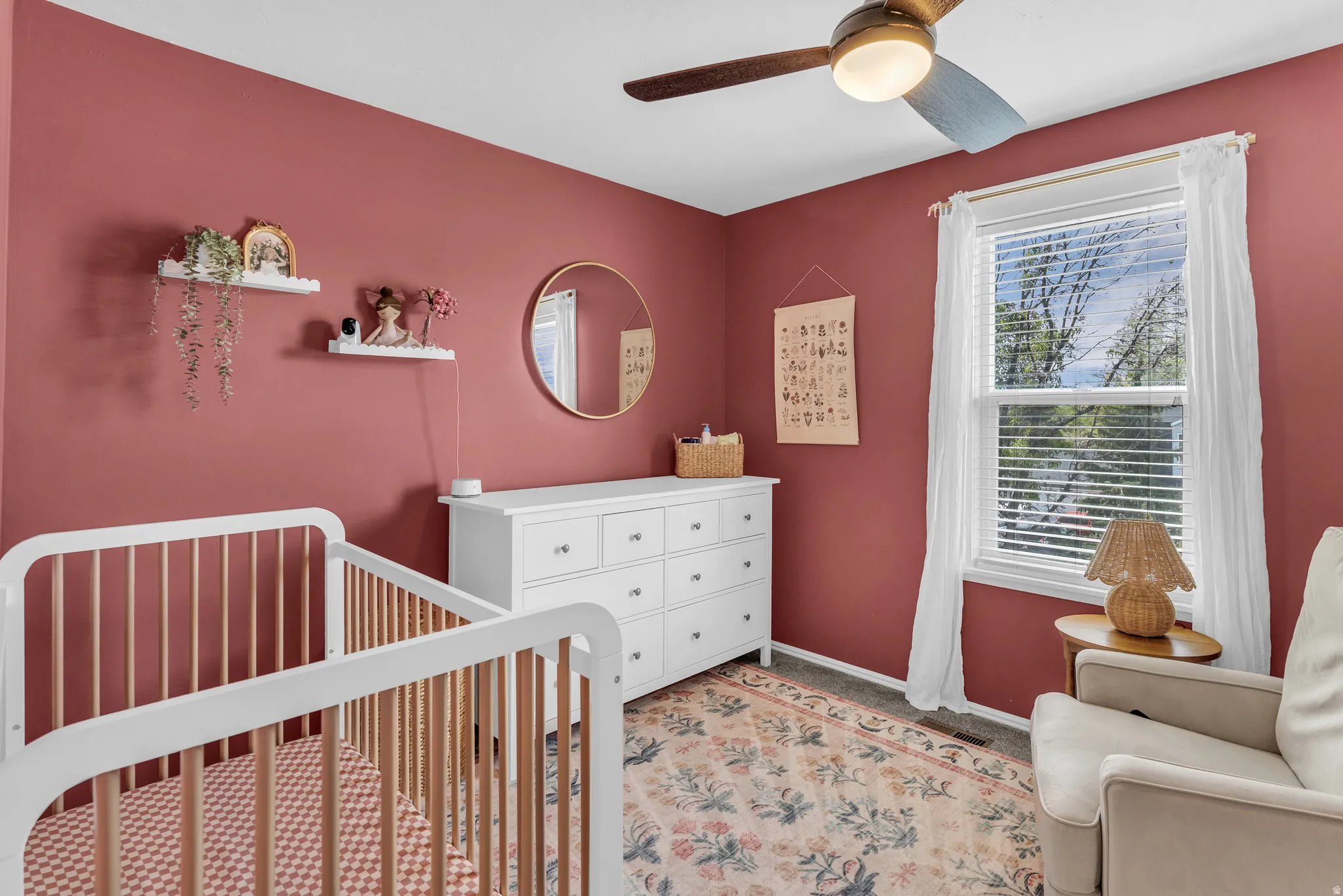 Bedroom with a crib, light carpet, and ceiling fan