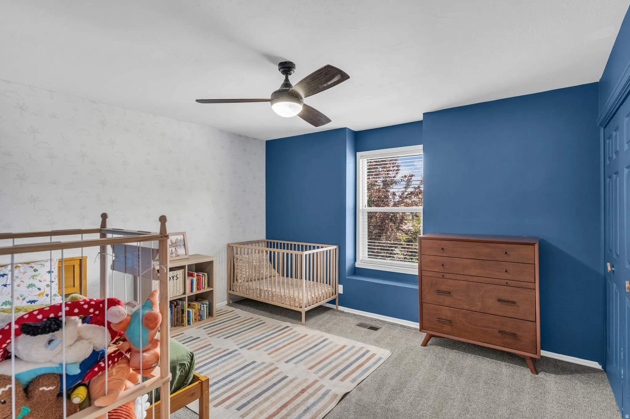 Bedroom featuring light colored carpet, a ceiling fan, a closet, and wallpapered walls
