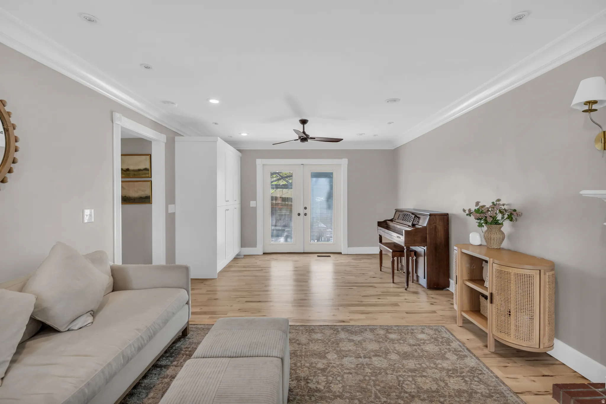 Living room featuring french doors, ornamental molding, light wood-style floors, a ceiling fan, and recessed lighting