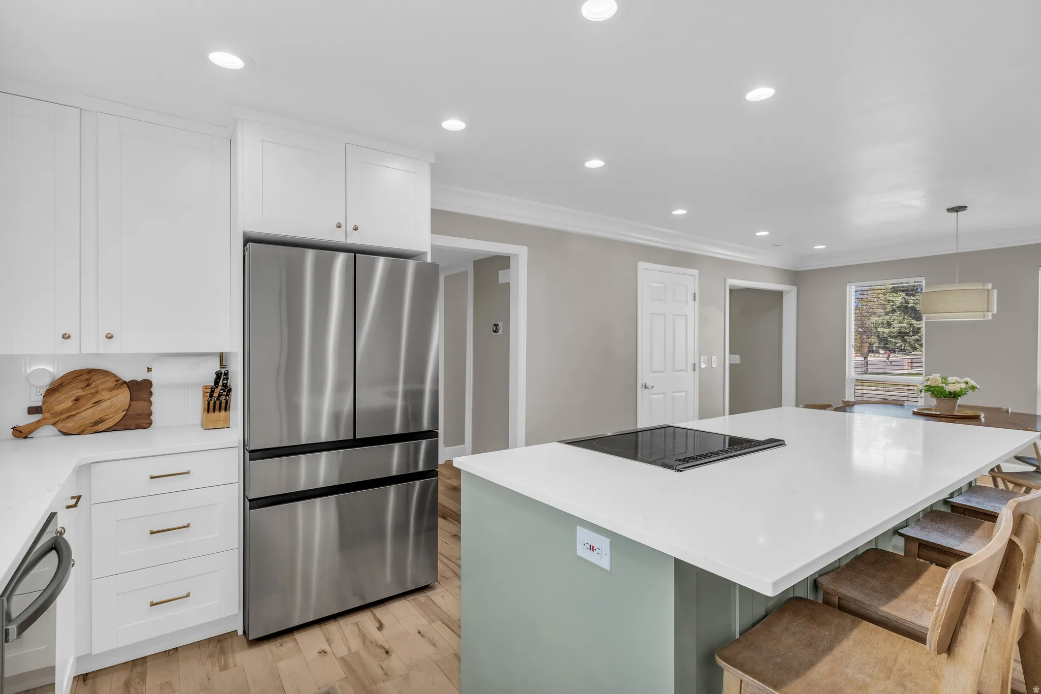 Kitchen featuring dual tone cabinetry, stainless steel appliances, a center island, light wood-type flooring, and light stone counters