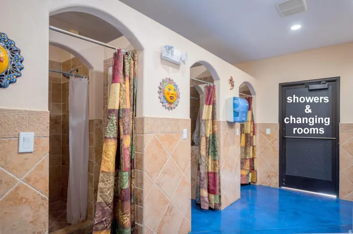 Interior space with a wainscoted wall, a stall shower, and tile walls