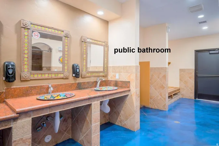 Full bath with tile walls, double vanity, a wainscoted wall, and recessed lighting