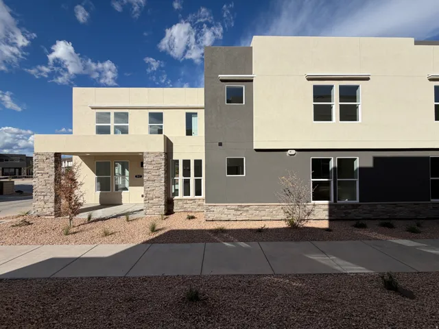 Modern multi-level residence featuring a neutral stucco exterior with contrasting dark grey accents