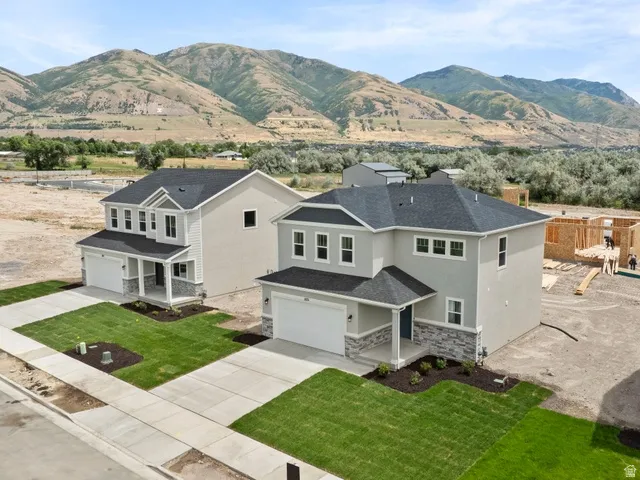 Newly constructed residence featuring a gray exterior with stone accents, a dark shingle roof, and an attached two-car garage