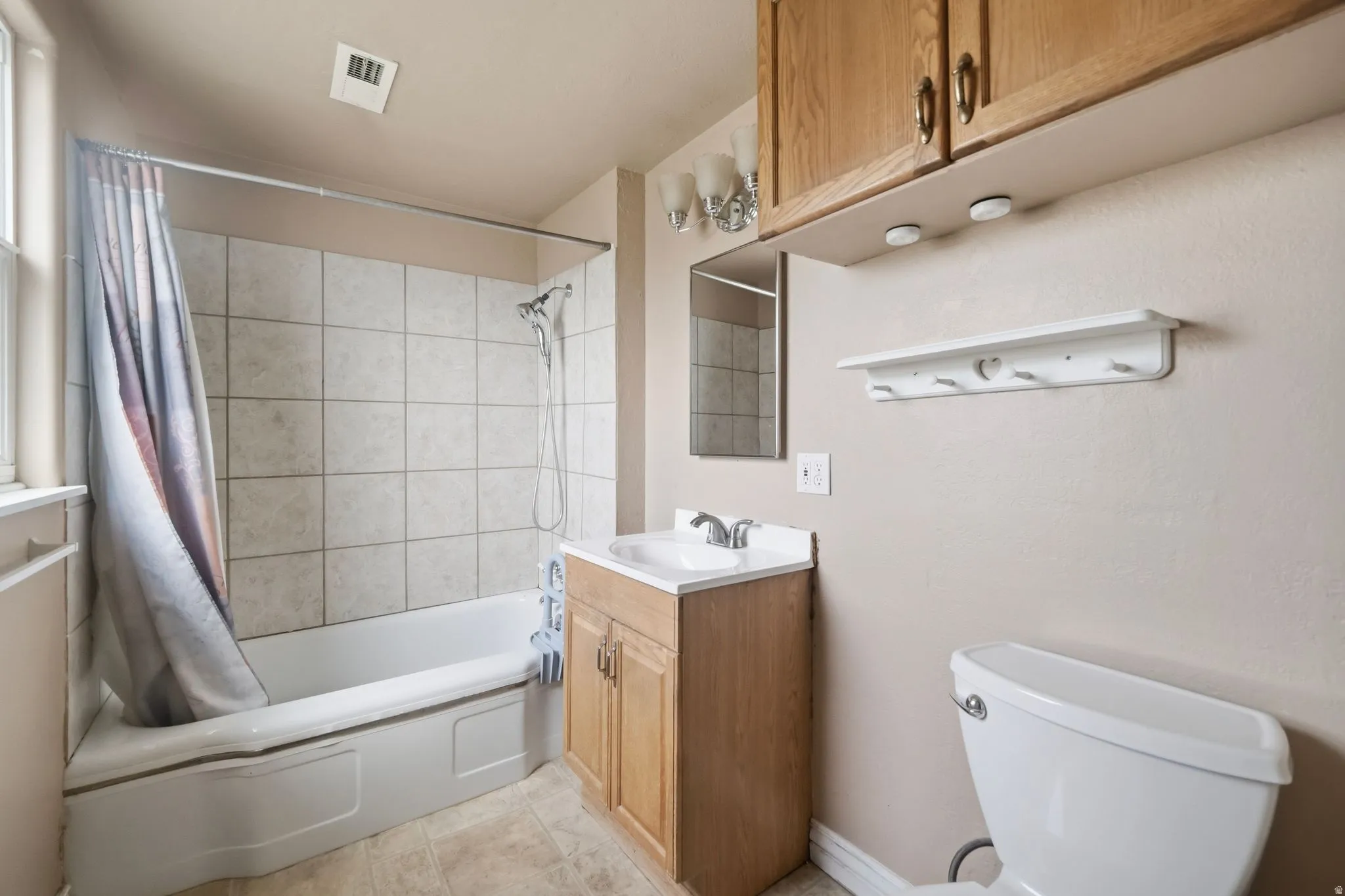 Full bath with vanity, shower / bath combination with curtain, and light tile patterned flooring