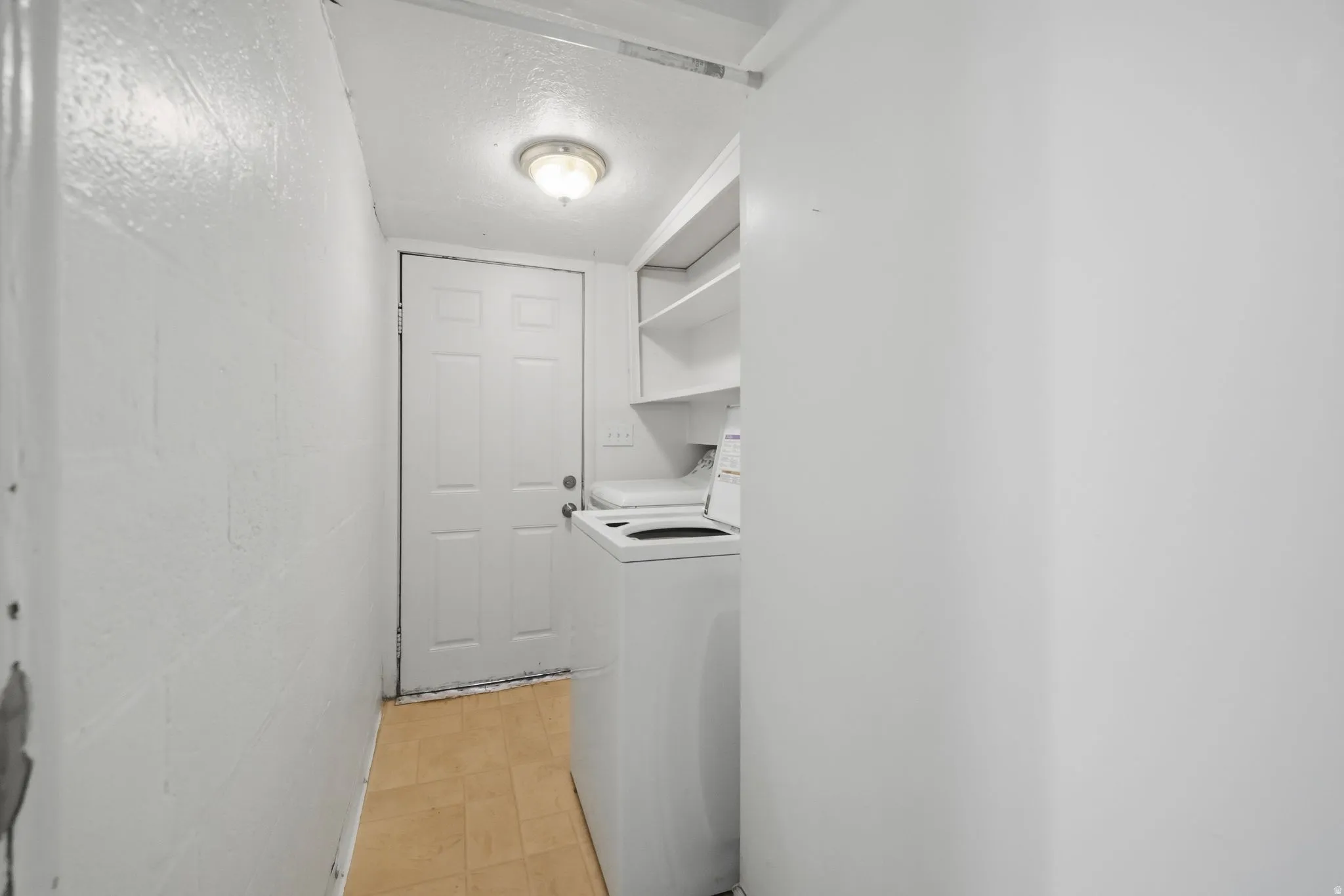 Laundry area featuring a textured ceiling and concrete block wall