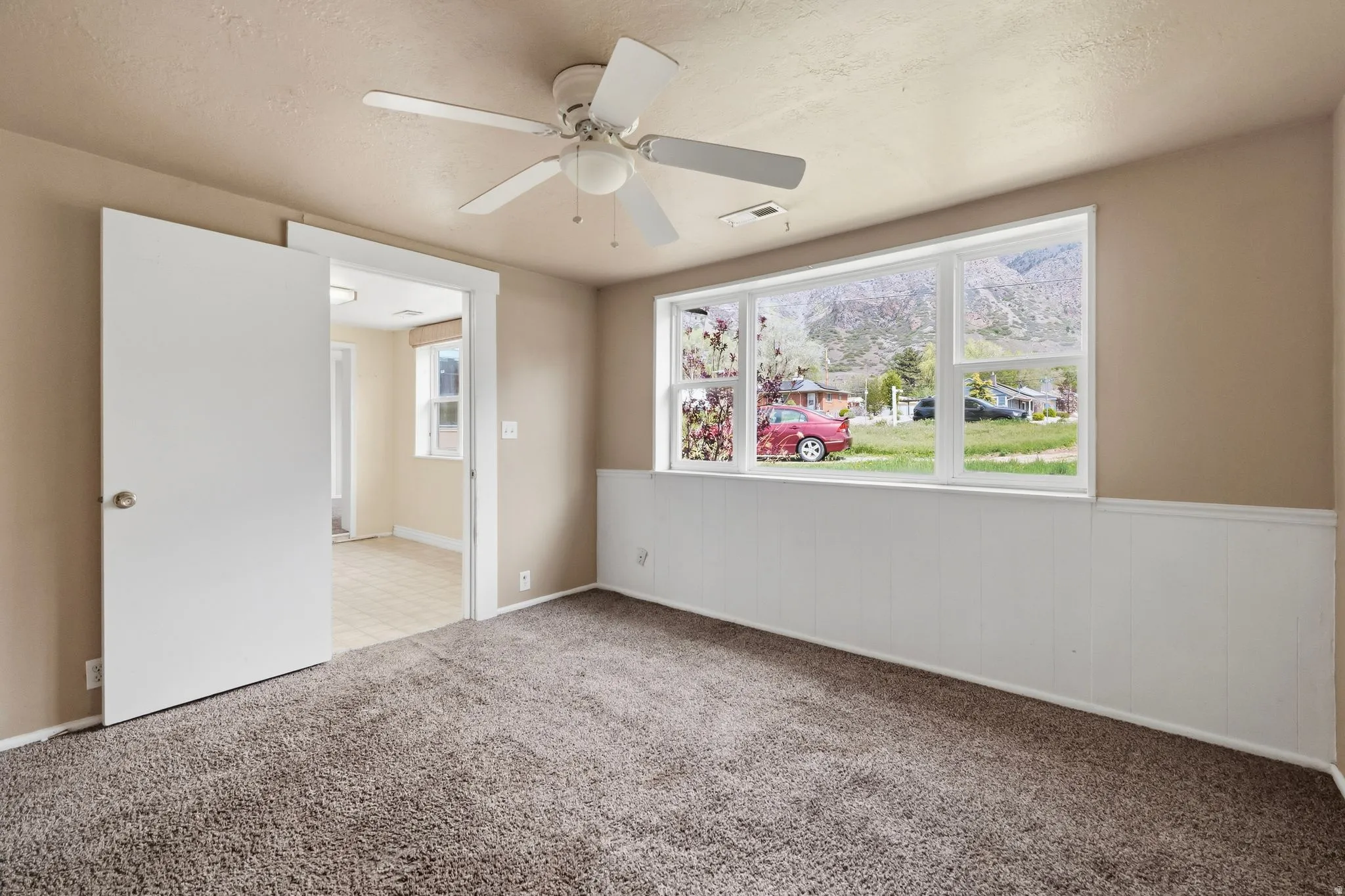 Spare room featuring ceiling fan, light carpet, and a textured ceiling