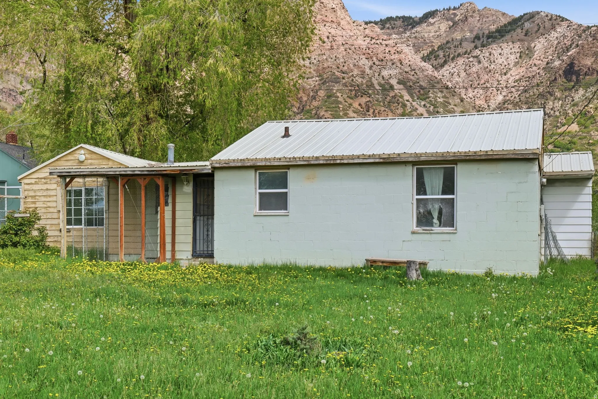 View of side of property with concrete block siding, a yard, a mountain view, and a metal roof