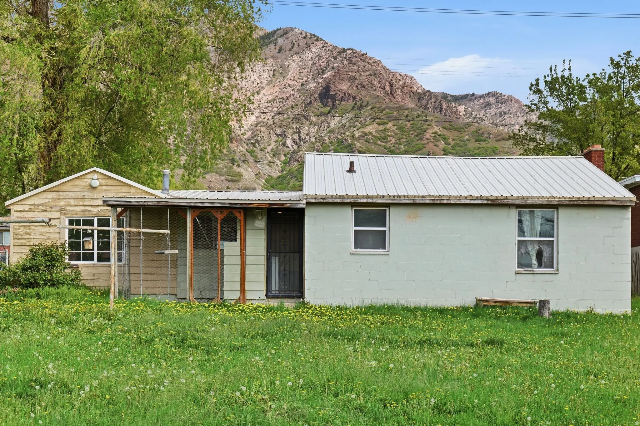 View of front of home with a mountain view, a front lawn, concrete block siding, and a metal roof