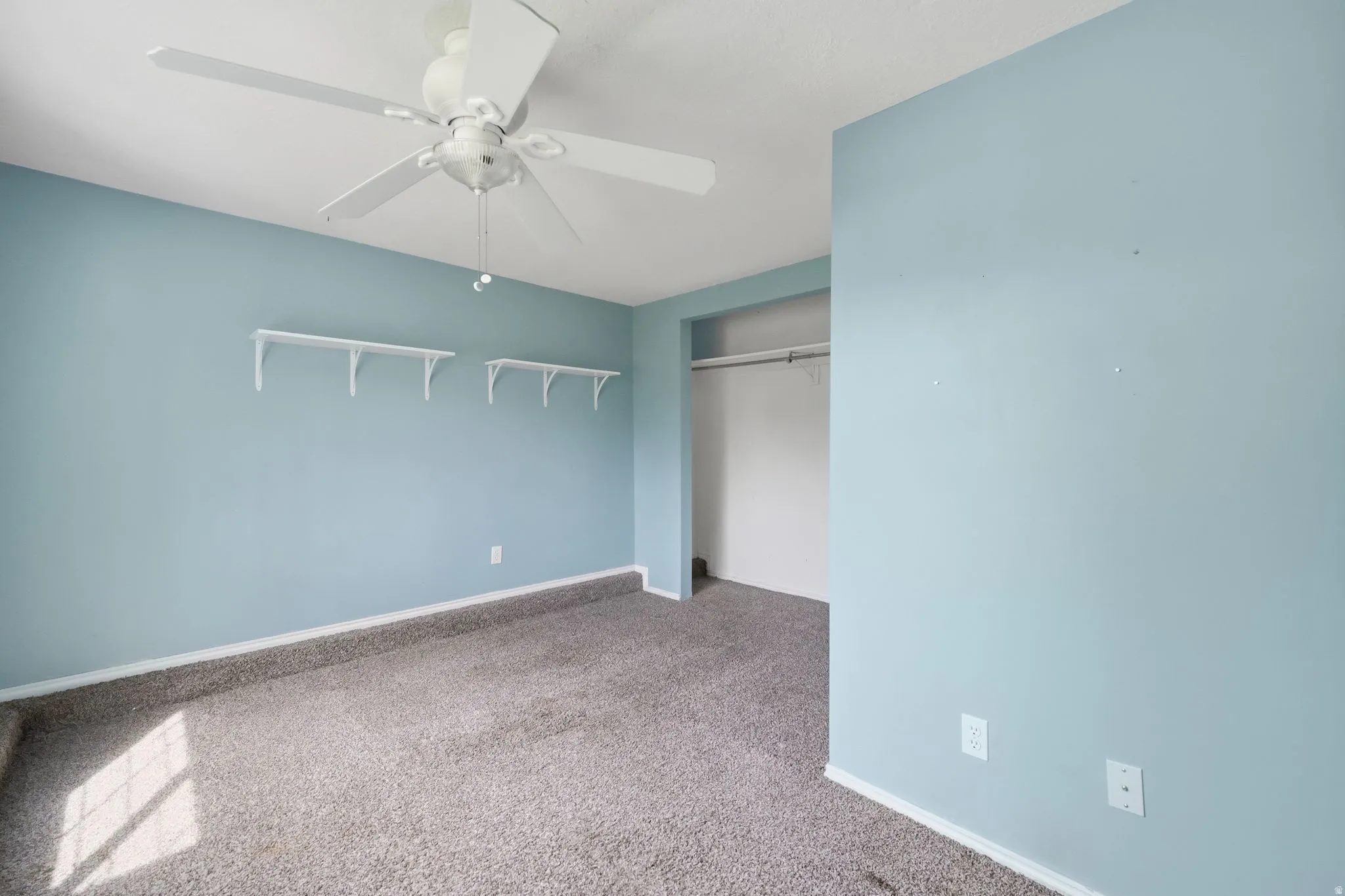 Unfurnished bedroom with light colored carpet, a closet, and ceiling fan