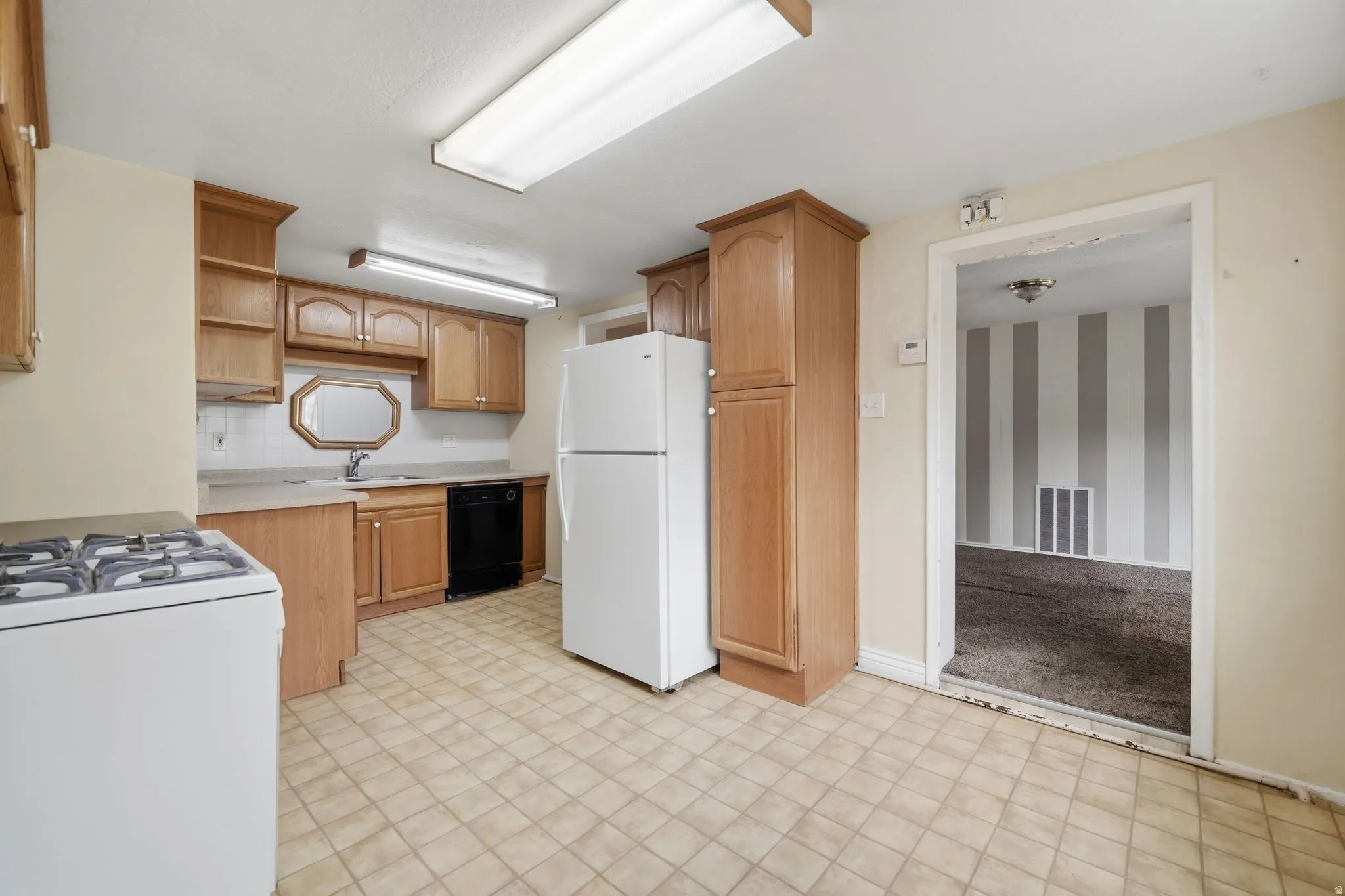 Kitchen with light countertops, white appliances, open shelves, light flooring, and decorative backsplash