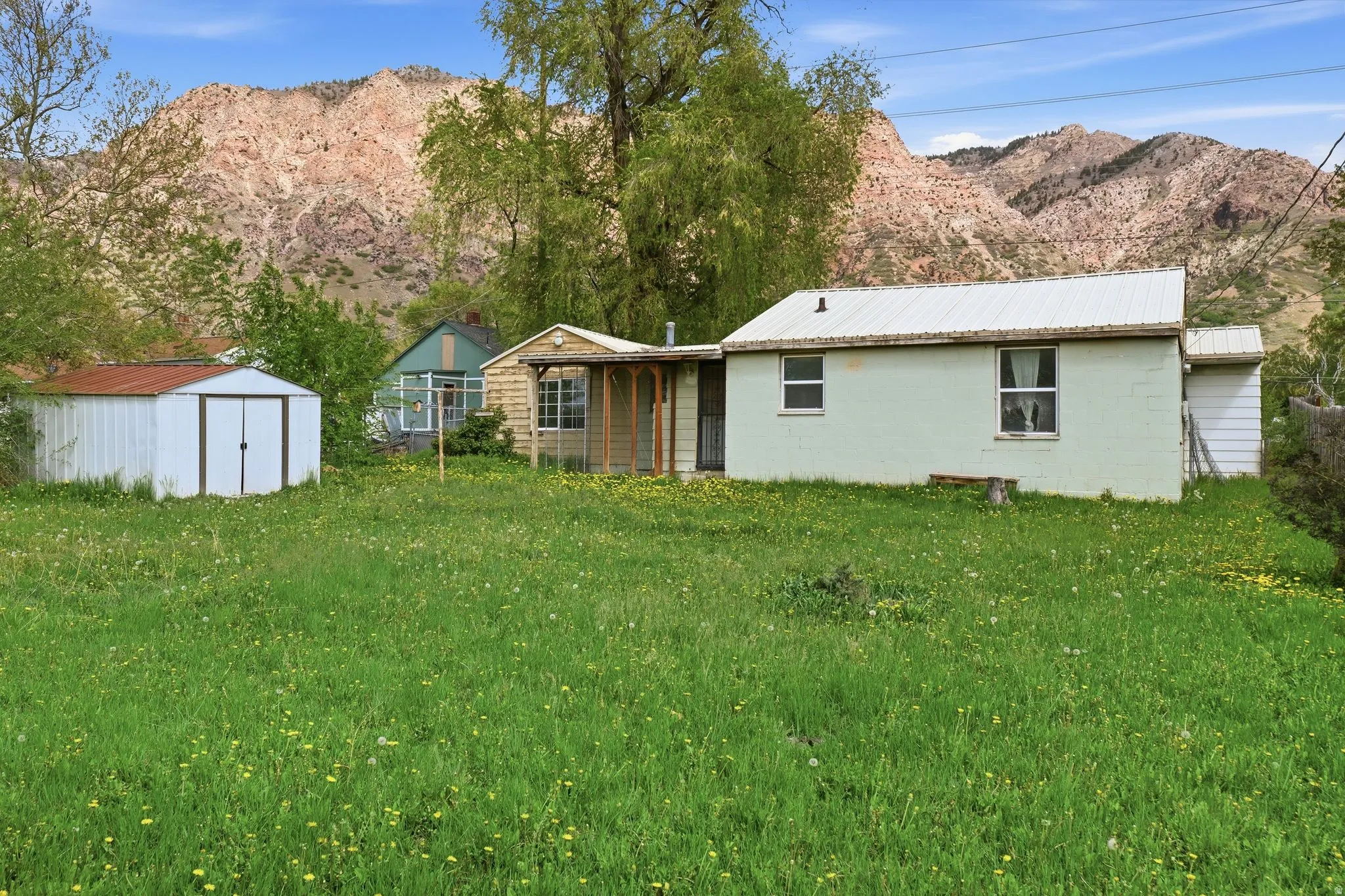 Back of house with a storage shed, a lawn, a mountain view, concrete block siding, and a metal roof