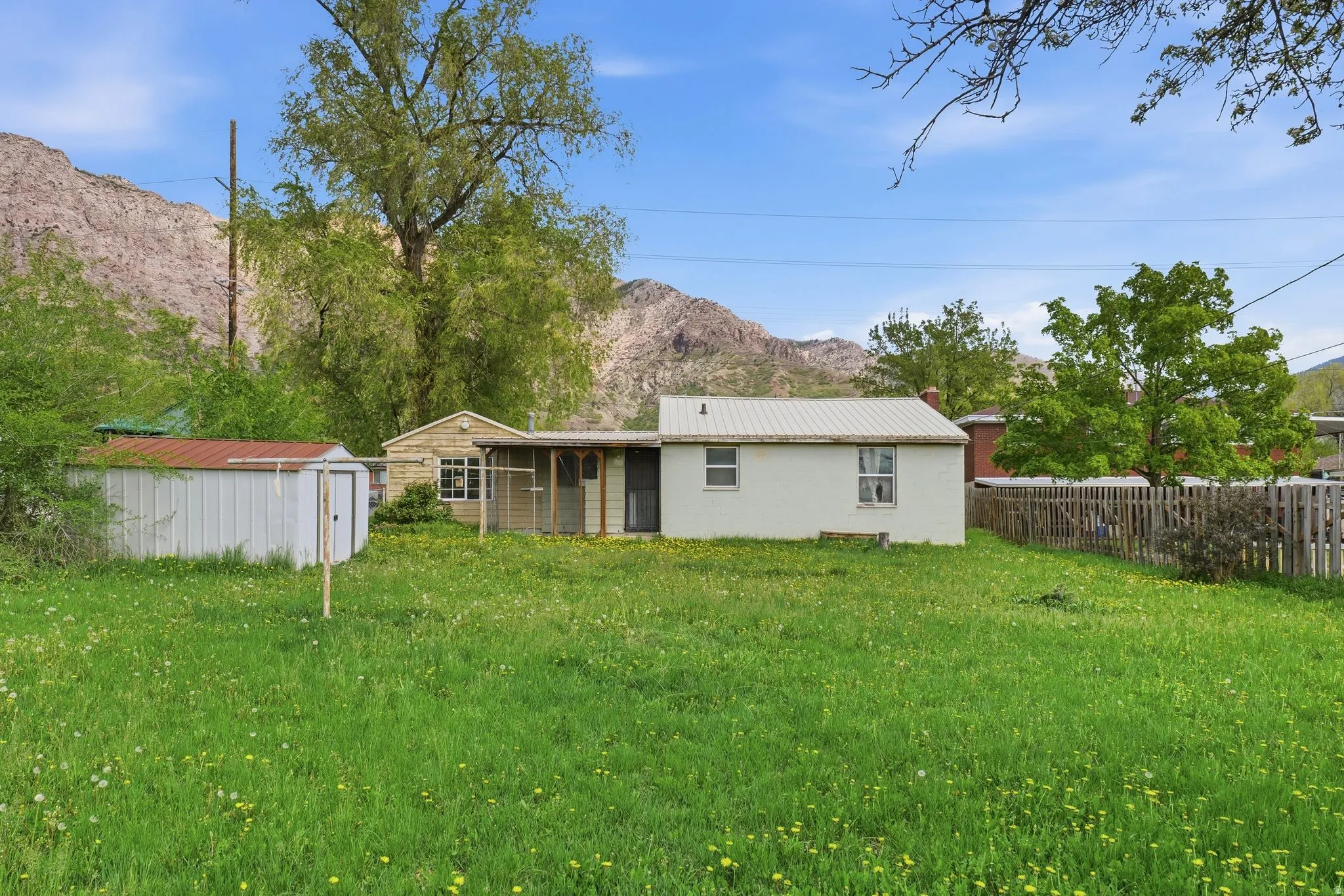 Back of house featuring a shed, a metal roof, a mountain view, and a lawn