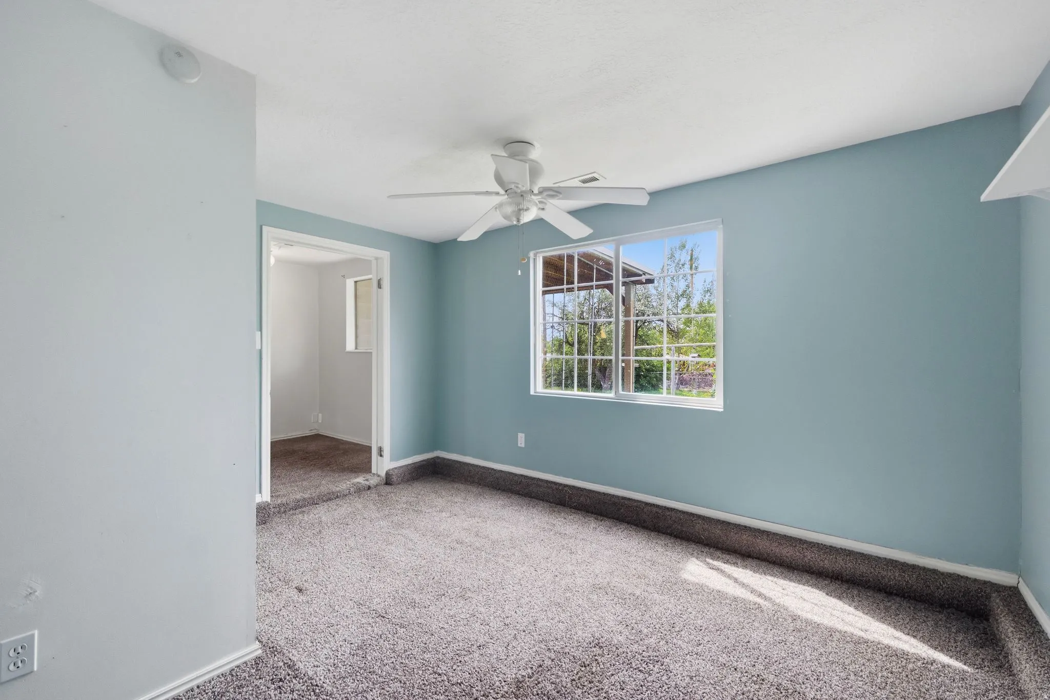 Empty room featuring light colored carpet and a ceiling fan