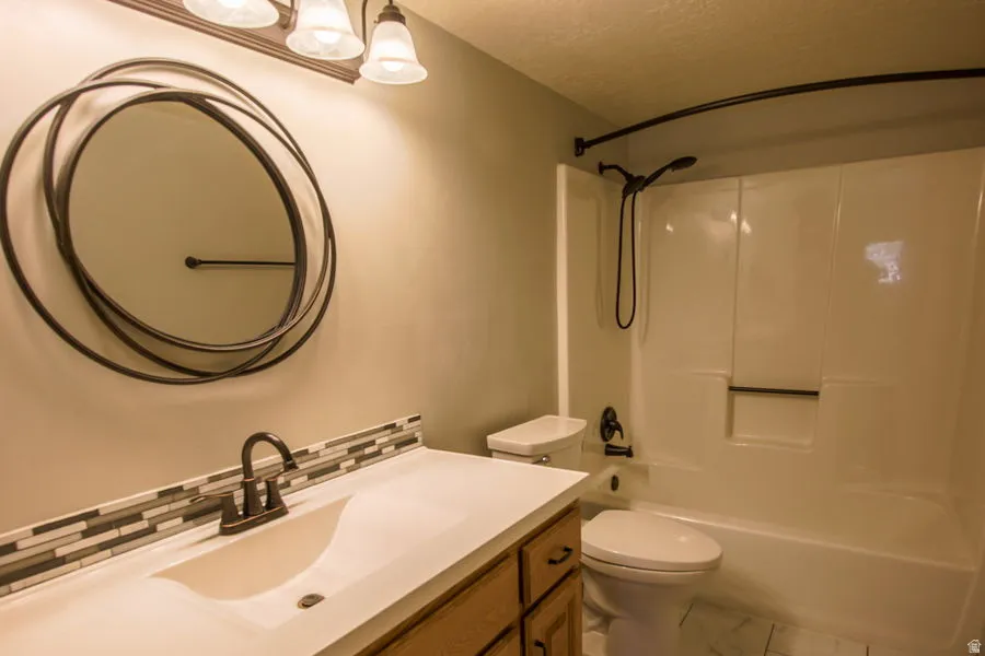 Downstairs updated full Bathroom featuring vanity, and tile backsplash. new floors