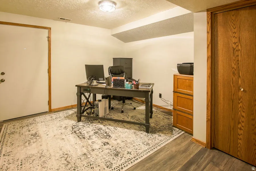 Office area with closet and wood finished floors and entry door to back yard. There are two downstairs exits.