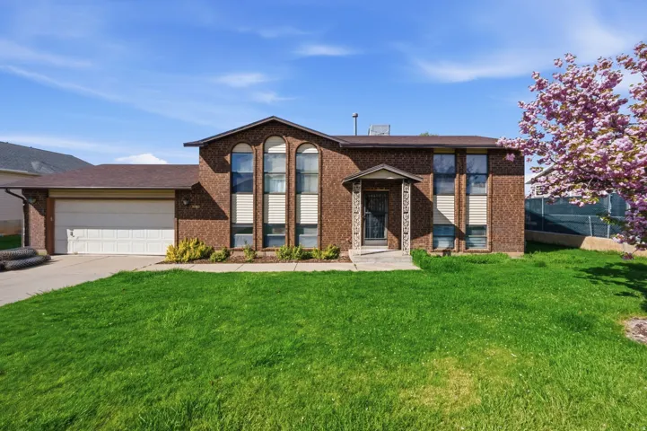 Split foyer home with a garage, brick siding, concrete driveway, and a shingled roof
