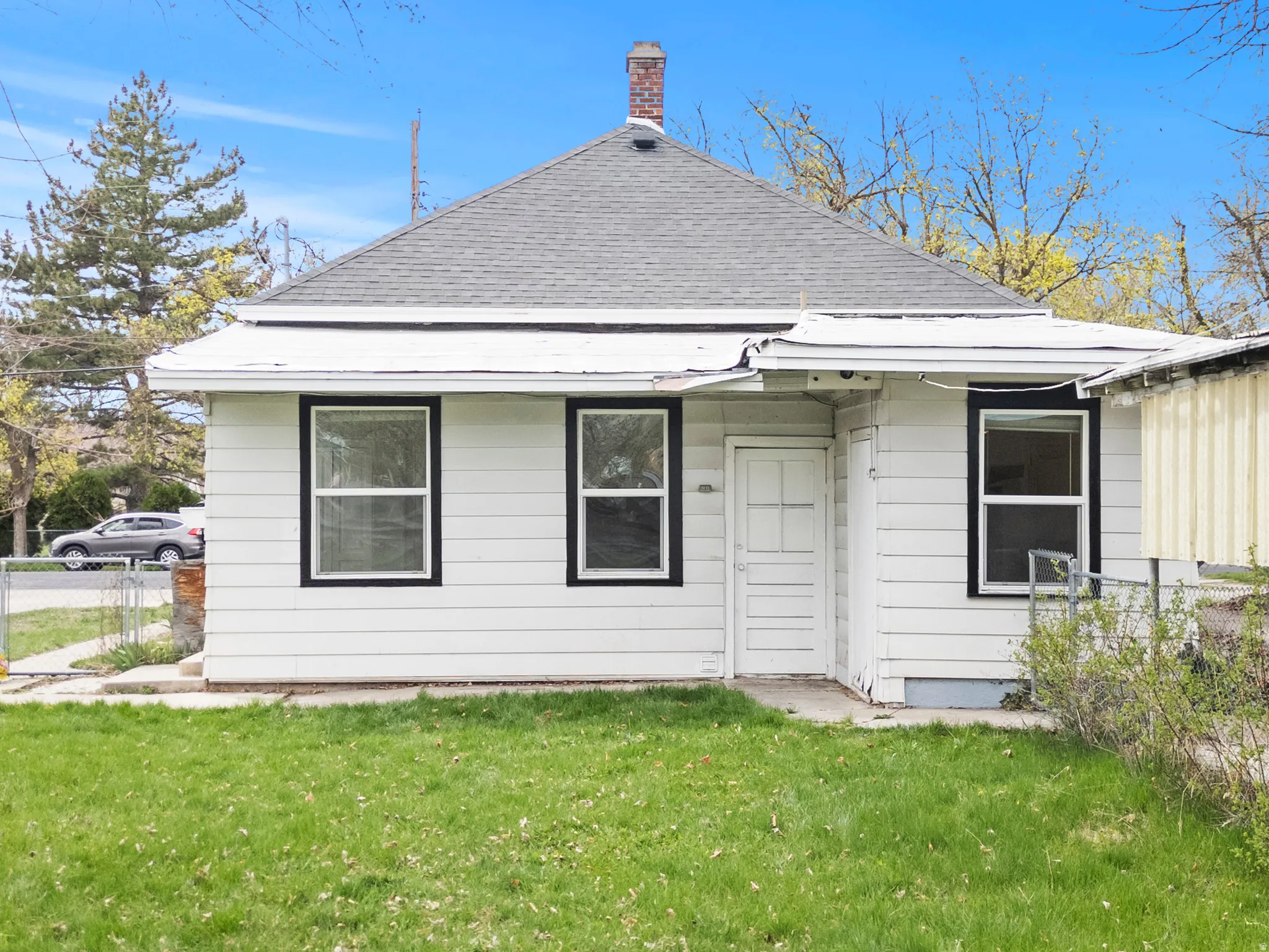 Rear view of property featuring roof with shingles, a lawn, and a chimney