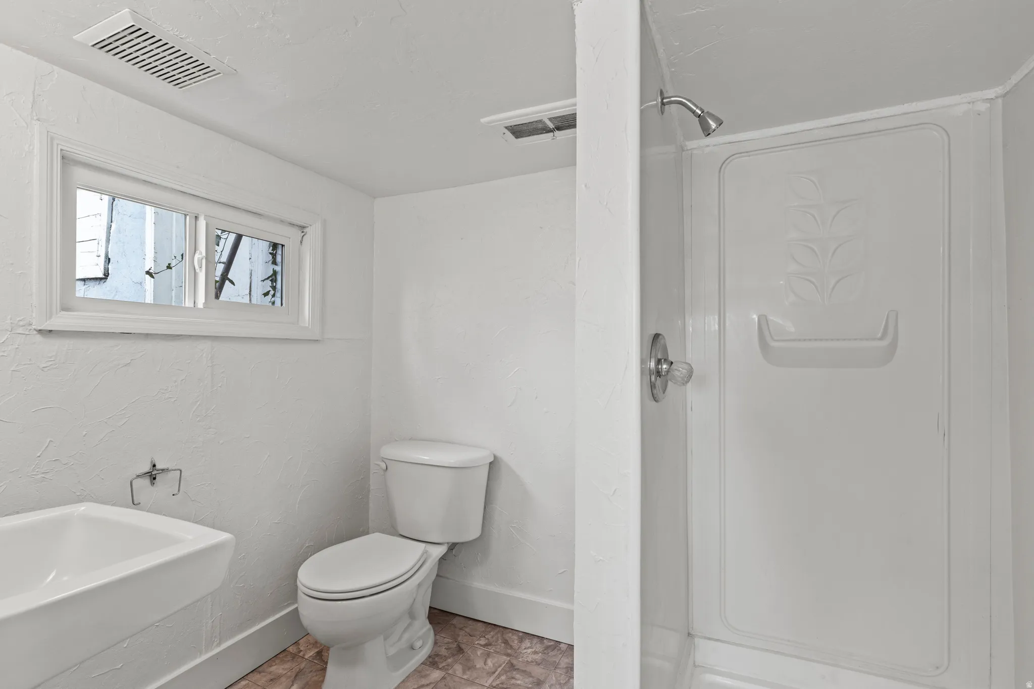 Bathroom with a stall shower and a textured wall