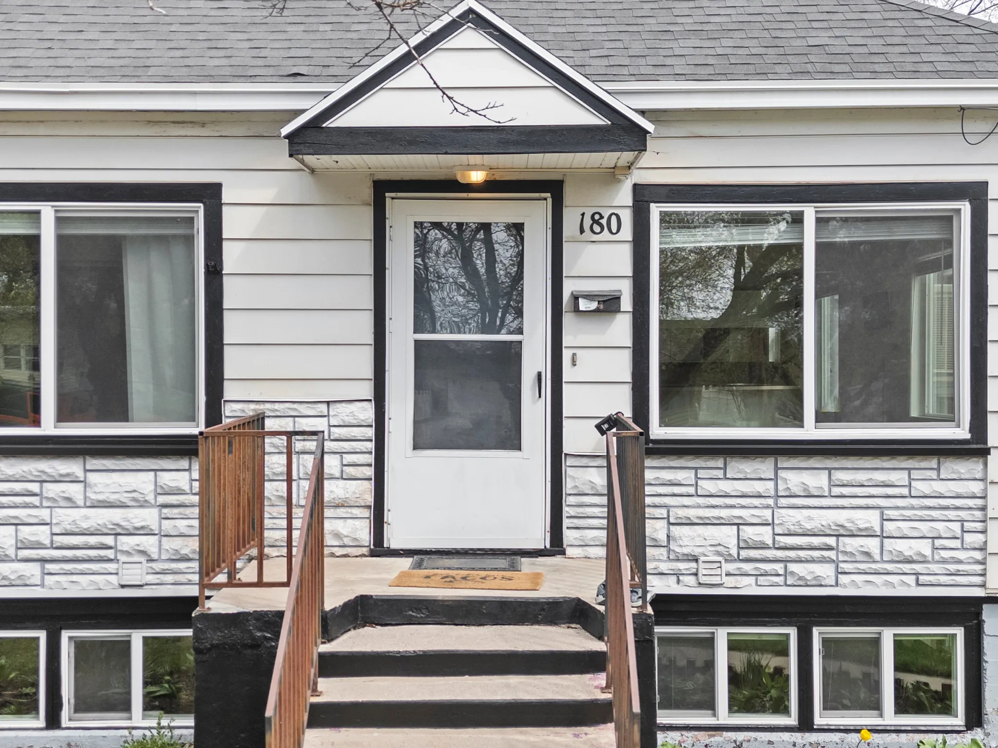 Doorway to property featuring stone siding and a shingled roof