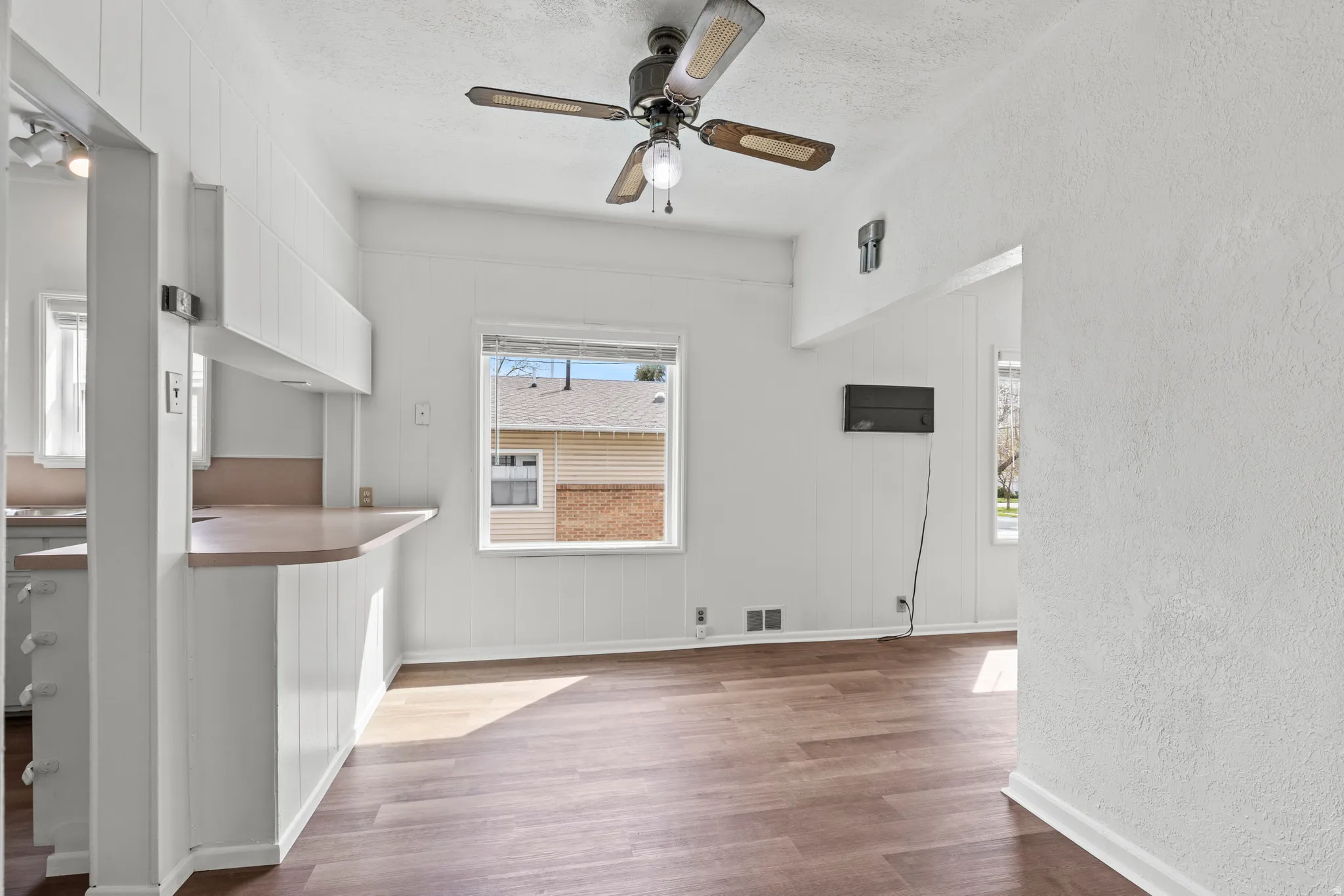 Unfurnished living room featuring vinyl floors, a ceiling fan, a textured wall, and a textured ceiling