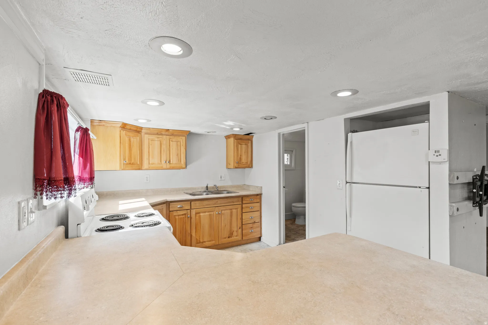 Kitchen with white appliances, light countertops, recessed lighting, a peninsula, and a textured ceiling