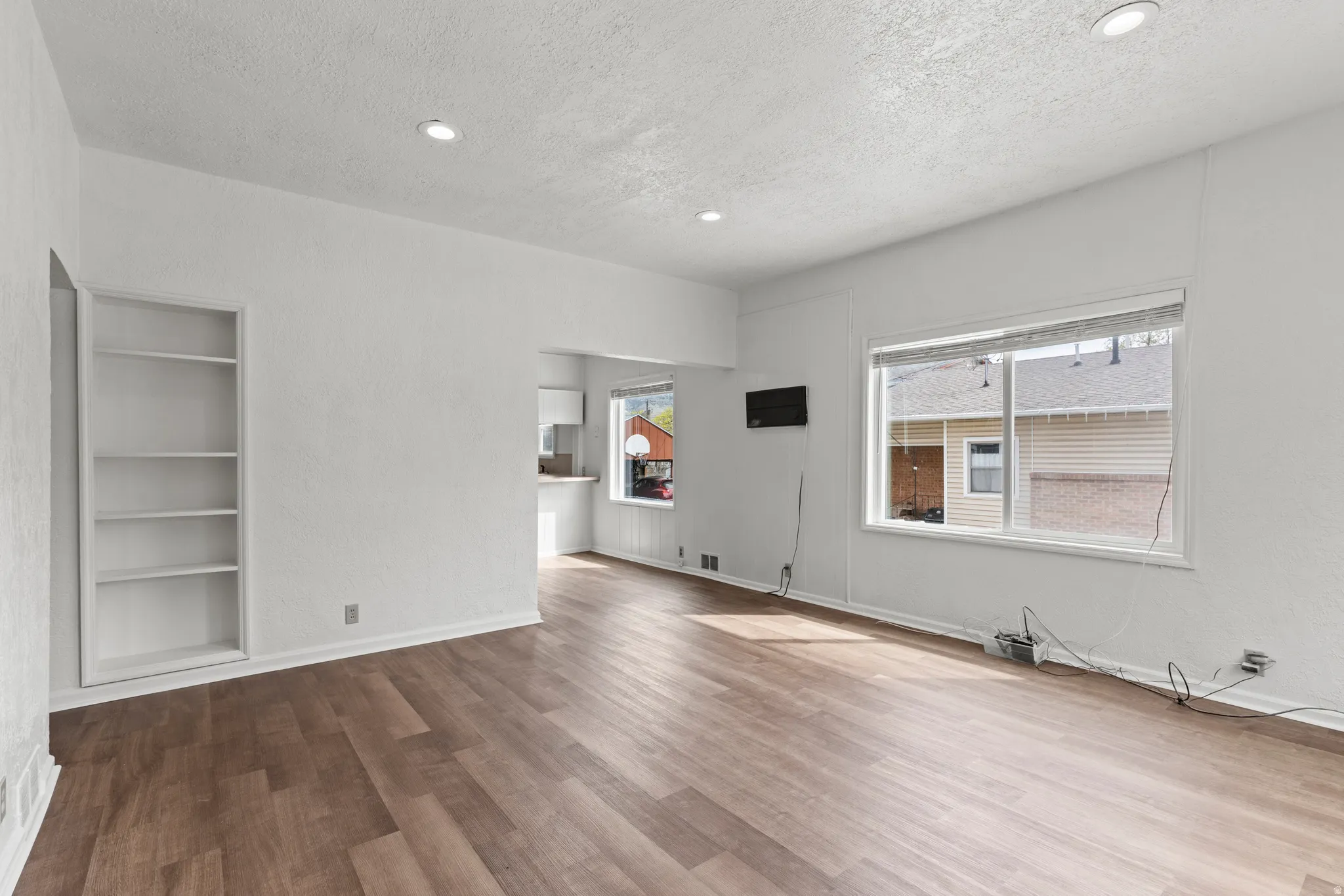 Unfurnished living room featuring built-in shelves, recessed lighting, vinyl floors, plenty of natural light, and a textured ceiling