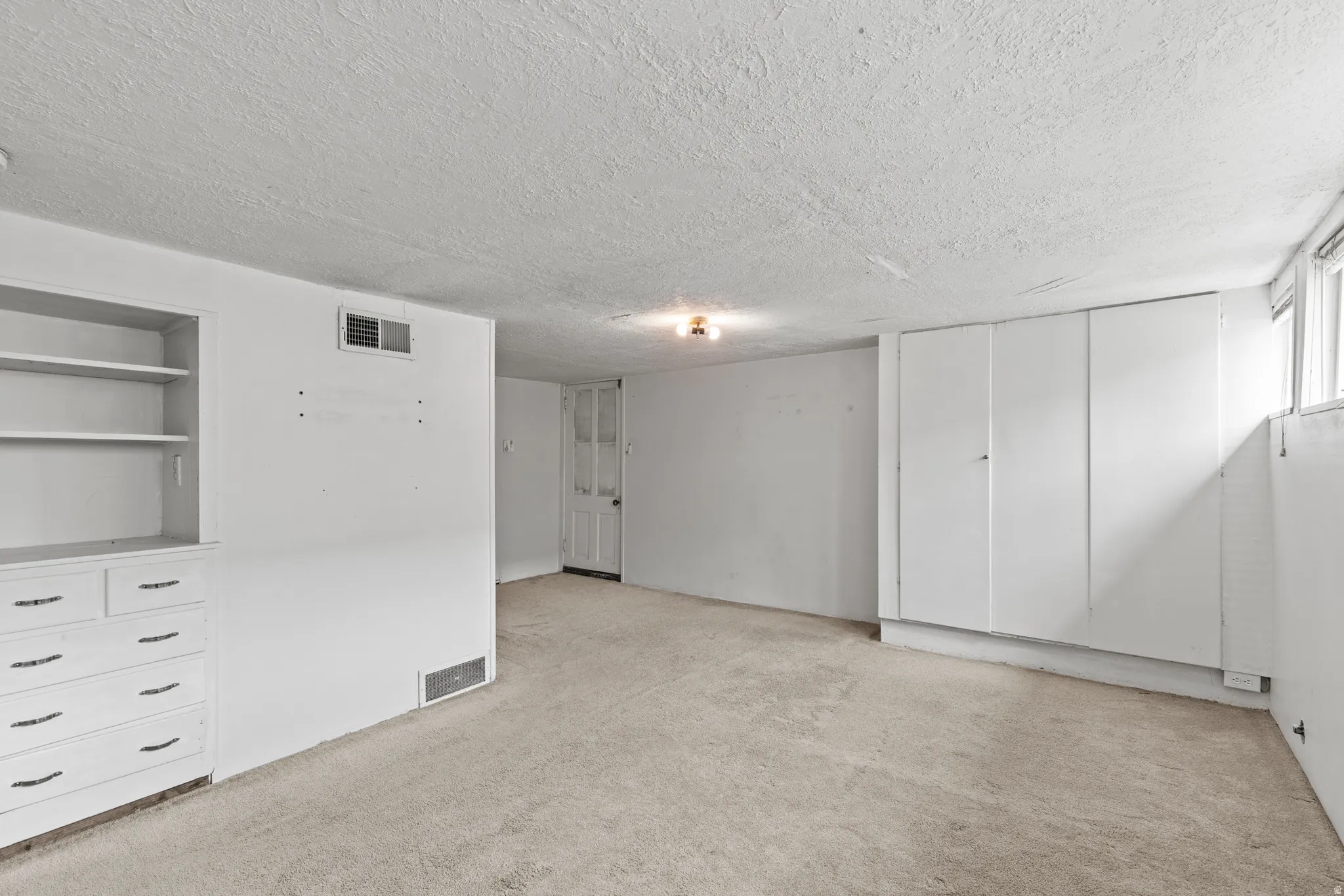 Unfurnished bedroom with light carpet and a textured ceiling